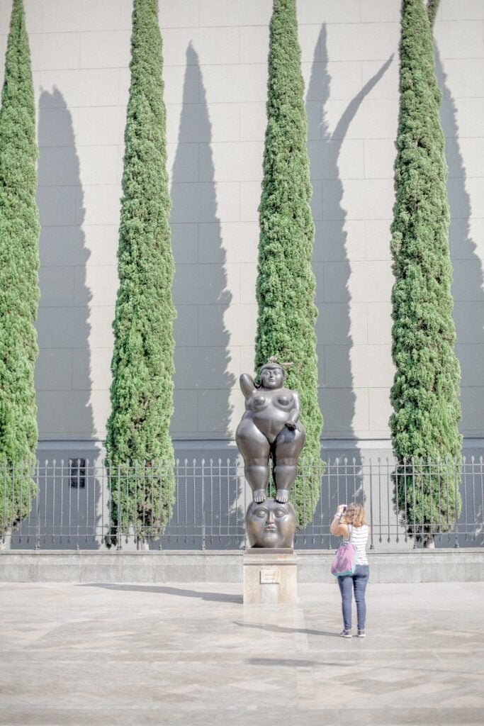 woman taking photo of nude woman statue