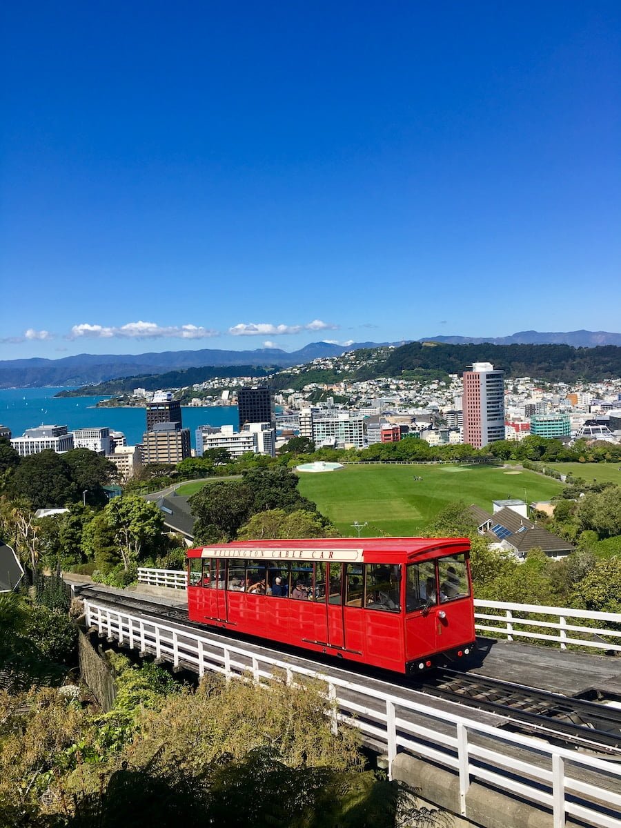 red train on rail with cityscape view underlue sky